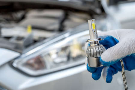 the mechanic replaces the halogen bulbs in the headlights in the car. auto technology