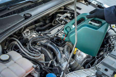 mechanic pouring oil to car engine. auto motor service. repairの写真素材