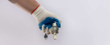 hand in protective glove holding led halogen headlight bulb,isolated
