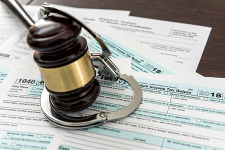 Law concept, 1040 finance tax form with gavel and handcuff. Crime and illegal systemの写真素材