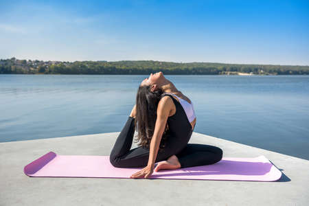 Young pretty fitness woman doing yoga poses, streching in the nature. Healthy lifestyleの写真素材