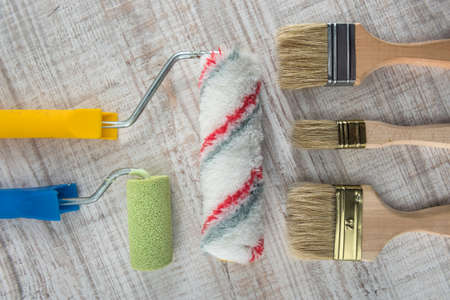 Set of paint brushes and rollers on wooden desk. All for repair