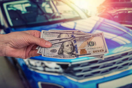 male hand dollar, take money on car background. business concept