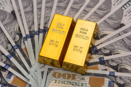 Expensive gold bar lying on dollar bills. save money concept