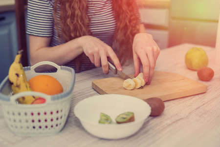 Happy young woman prepare doing fruits salad for diet in kitchen, healthy food. Diet concept.の写真素材
