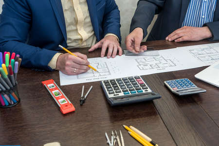 Two businessman working with house architectural plan at office desk. Teamwork about blueprintの写真素材