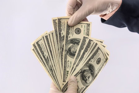 male hand give dollar to pay in protective gloves for safety isolated on white background. medical...