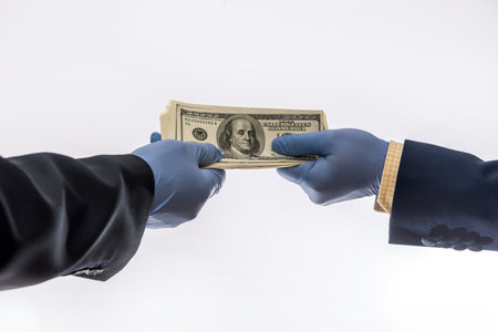 sharing dollars between two businessman for pay goods in medical gloves, isolated on white background. coronavirus pandemic periodの写真素材