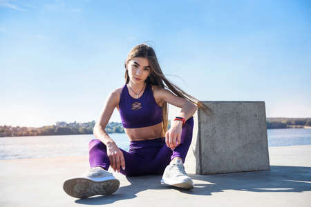 girl in sports uniform resting after morning exercises on the shore of the lake. health and beauty conceptの写真素材