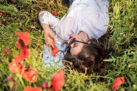 Young woman is standing near blooming poppy field. happy girl at outdoor lifestyleの写真素材