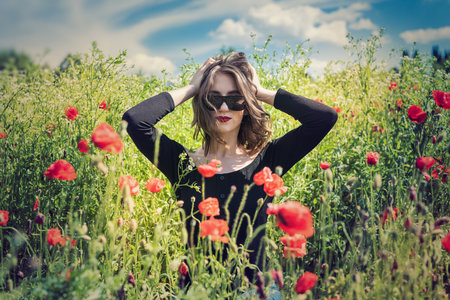 Young woman is standing near blooming poppy field. happy girl at outdoor lifestyleの写真素材