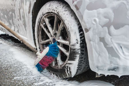 female hand cleaning car in service with tools soap foam and water. wash autoの写真素材