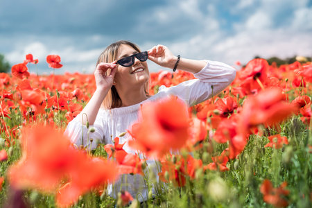 Happy young slim girl walk in red poppies field, spending time, summerの写真素材