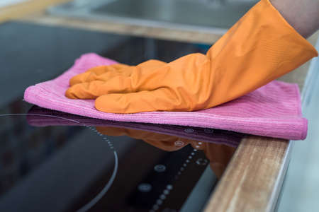 woman washing modern cooktop cooking panel in kitchen. cleanの写真素材