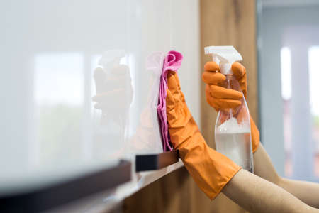 woman while cleaning the surface of a kitchen desk with sponge in her rubber gloves. houseworkの写真素材