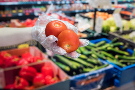 the buyer in gloves chooses vegetables during a pandemic due to a new dangerous virus, coronavirusの写真素材