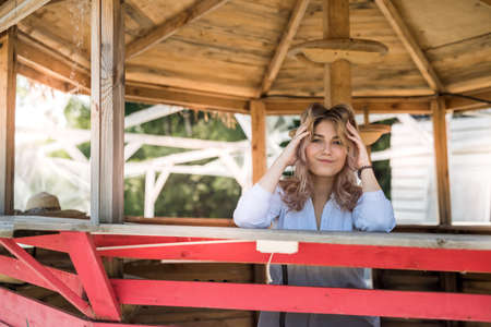 Portrait of smiling youthful woman which enjoying vacation time, near sand beach in wooden gazebo.の写真素材