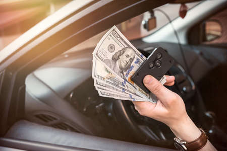 man rent car for trip and holding dollar and auto key. finance conceptの写真素材