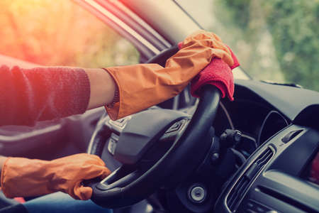 female hand cleaning her car interior from coronavirus and pandemic with disinfectant fluid. wash vechileの写真素材