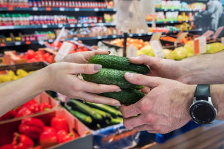the seller gives vegetables to the buyer in the store. the concept of shopping and a healthy lifestyleの写真素材