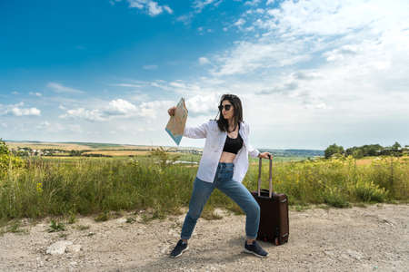 Pretty young woman stand and look at the map on the road, enjoy summer vacation at natureの写真素材
