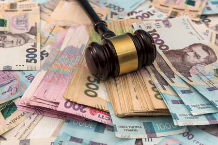 wooden hammer on ukraine money as background. 500 and 1000 new uah grivna. legal or save concept