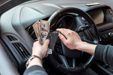 man hold dollar and car key for pay rent or bribe. financeの写真素材