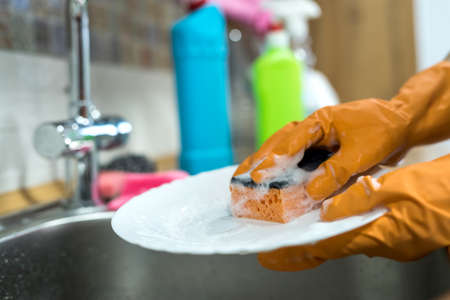 woman hands rinsing plate under running water in the sink. houseworkの写真素材