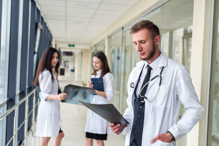 Three interns looking at an X-ray of the lungs to determine if there is pneumonia from the coronavirus. medical conceptの写真素材