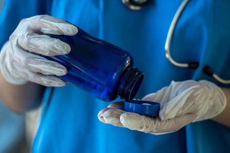 nurse in blue uniform holding bottle with white pills. medical conceptの写真素材