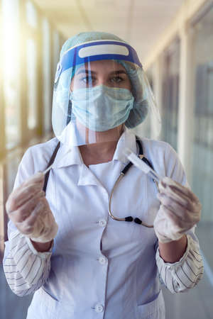 young nurse in protective suit and face shield holding a positive blood test result for covid-19 in laboratory. pandemicの写真素材