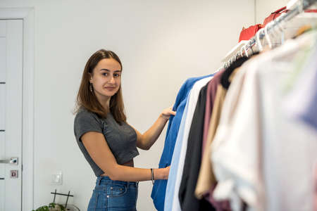 Smiling woman shopper choosing new garments at fashion story. lifestyle