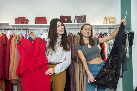 Two women choose modern dress in a store. Black friday shopping concept