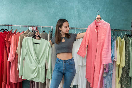 Smiling woman shopper choosing new garments at fashion story. lifestyleの写真素材