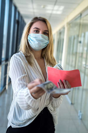 charming young lady in a medical mask holding an envelope with money in the mall. finance concept