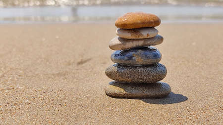 zen stones laid out by hand lying on sand of sea beach. summer holidaysの写真素材