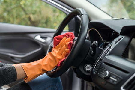 Hand with glove using wet wipe and antibacterial spray cleaning car interiorの写真素材