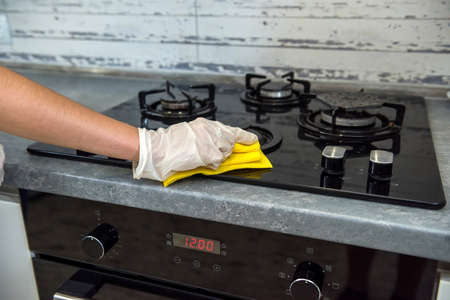female hand in white gloves cleaning with a foam gas stove with a glass surface. houseworkの写真素材