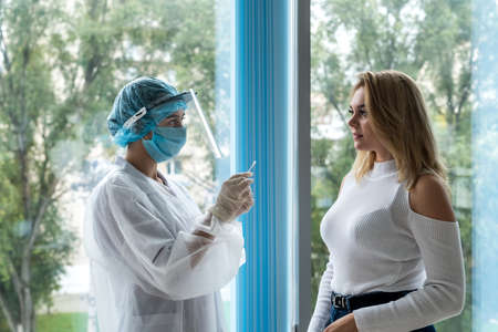 female doctors taking sample with cotton swab in potential patient in modern clinic