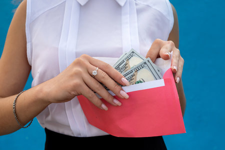beautiful young business lady holding an envelope with dollars on a blue background. concept of...
