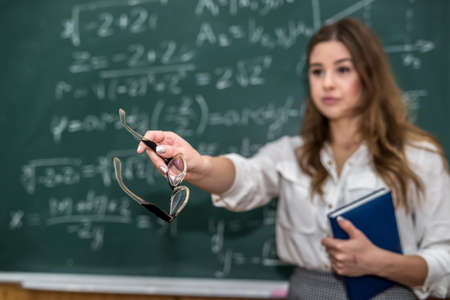 After writing a mathematical equation, the young teacher calls the student to the board so that he can explain everythingの写真素材