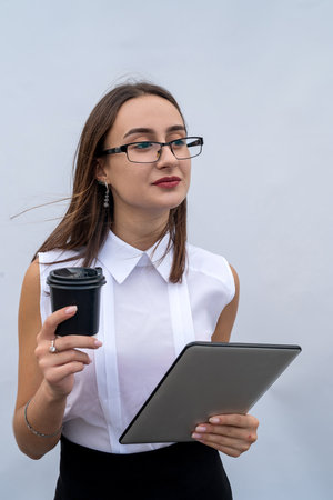 Serios businesswoman with cup of coffee and tablet computer isolated on white gray backgroundの写真素材