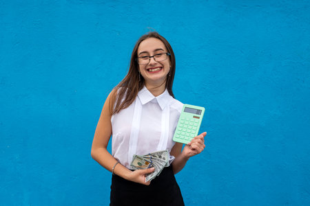Business young lady with green calculator isolated on blue background. finance conceptの写真素材