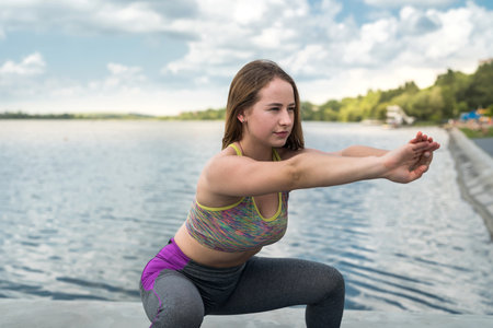 Portrait of pretty fitness woman in sportwear doing stretching exercise outdoor. Sport for healthの写真素材