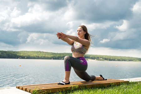 Young slim woman doing yoga exercises near the lake. concept of calm and meditation