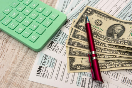 Financial document us 1040 tax forms with dollars, calculator and pen. Tax time conceptの写真素材