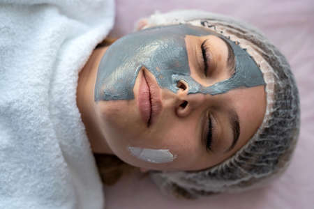 young girl relaxing at spa, lying in bed with facial mask. Spending time for selfの写真素材