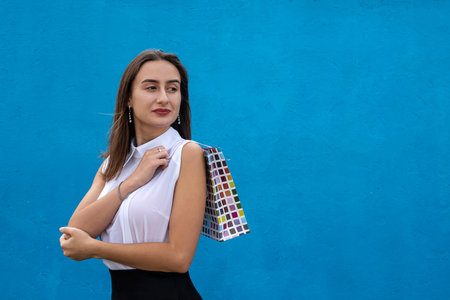 Beautiful woman in business cloth holding shopping bags isolated on blue background. Shopping...