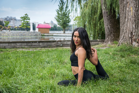 Beautiful fitness trainer doing yoga exercises on stretching and flexibility near lake. health...