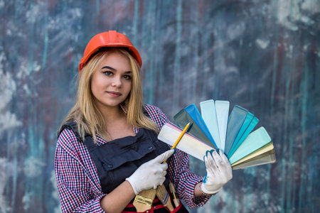 female painter in uniform and helmet with paint charts. construction and building concept